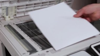 Bir ofis çalışanı tarayıcıdaki A4 kağıdını tarıyor.