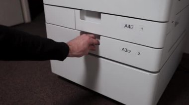  Bir ofis çalışanı yazıcı tepsisine bir yığın kağıt koyar.