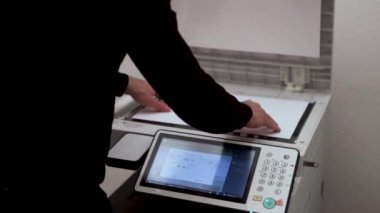 Bir ofis çalışanı tarayıcıdaki A3 kağıdını tarıyor.