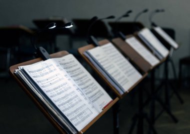 Music stands with musical notes in the rehearsal room. The music stands have lanterns attached to them for lighting. clipart