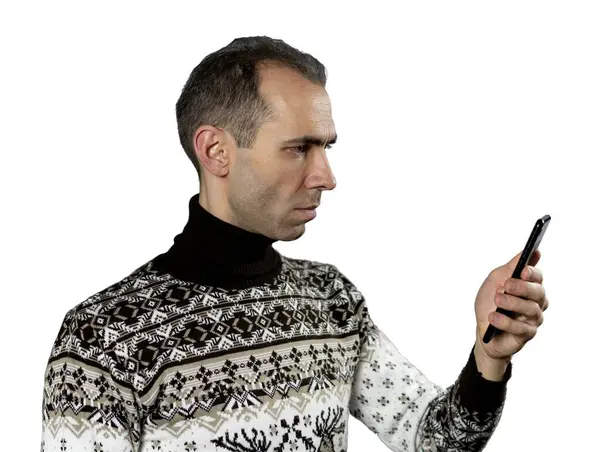 Rahat bir kazak giyen orta yaşlı bir adam akıllı telefonuna bakıyor. Onun ifadesi düşünceli ya da hafifçe şaşırmış. Beyaz şeffaf arkaplan