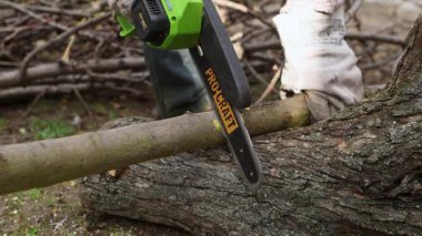 Elektrikli testereyle bir kütük kesiyordum. Ağaç dalını kesiyorum. Ağaç kesiyorum. Yakacak odun topluyorum. Talaşlar her yöne uçar.