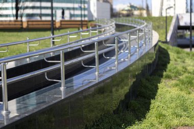 Bir kaldırım boyunca yer alan ve yayalar için hem güvenli hem de estetik cazibe sağlayan cilalı paslanmaz çelik korkuluklar.