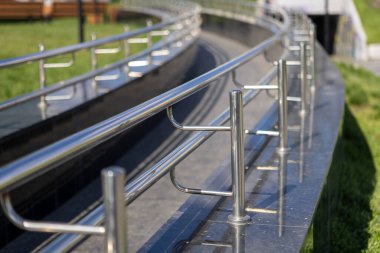 Bir kaldırım boyunca yer alan ve yayalar için hem güvenli hem de estetik cazibe sağlayan cilalı paslanmaz çelik korkuluklar.