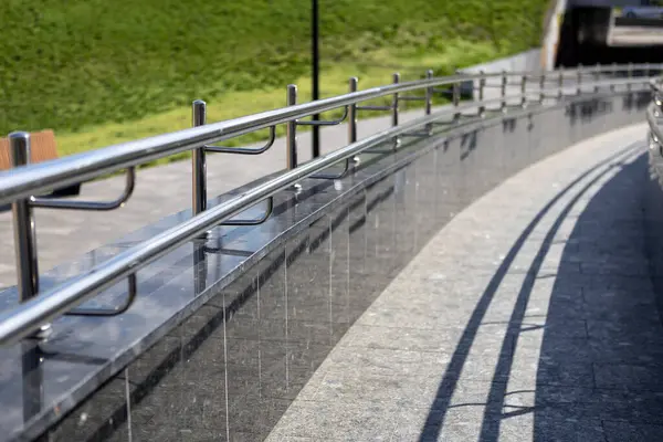 Bir kaldırım boyunca yer alan ve yayalar için hem güvenli hem de estetik cazibe sağlayan cilalı paslanmaz çelik korkuluklar.