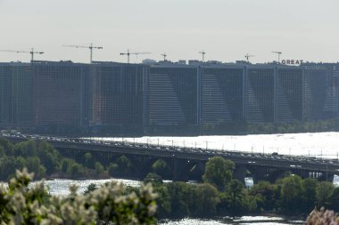 2025.05.01, Kyiv, Ukrayna: Büyük bir şehirde inşaat halindeki bir konut kompleksinin, kısmen inşa edilmiş yapıların üzerinde vinçlerin yükseldiği bir manzarası. İskeleler, beton çerçeveler ve yoğun faaliyet kentsel büyüme ve kalkınmayı yansıtıyor.