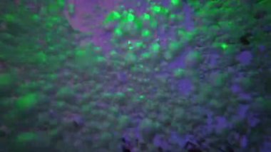 Kabarcıklar parlak ve renkli ışıklarla aydınlatılan parlayan havuz suyunda kaotik bir şekilde hareket ederler. Parlayan yansımalar soyut, rüya gibi bir model yaratır, hareket, ışık ve sıvıyı büyüleyici bir görsel ekrana karıştırır.