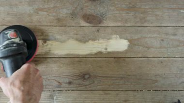 Zımpara makinesiyle ahşap zemini zımparalayan işçilerin yakın çekimi. Tahta, tedaviden sonra temiz kumlu alanlarla kalıyor..