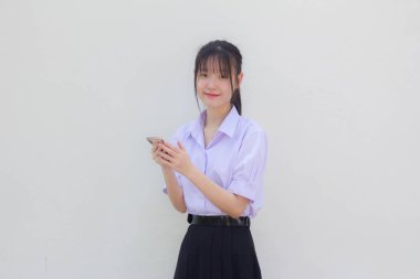 Asya Taylandlı lise öğrencisi üniforması güzel kız telefonunu kullanıyor ve gülümsüyor.