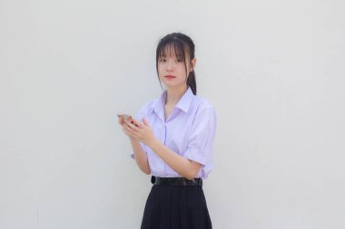 Asya Taylandlı lise öğrencisi üniforması güzel kız telefonunu kullanıyor ve gülümsüyor.