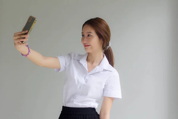 thai adult student university uniform beautiful girl using her smart phone Selfie