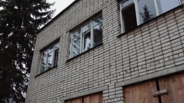İki katlı tuğla bir binanın camları kırılmış. Gri gökyüzüne karşı savaş alanında tahrip edilmiş terk edilmiş bir bina. Yüksek kalite 4k görüntü