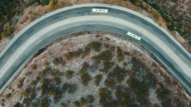 Aerial top view of two tour buses driving down a curvy mountain road. Travel journey transport and vacation concept. High quality 4k footage