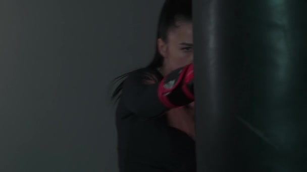 身穿拳击手套的咄咄逼人的强壮女人有力地打了一袋拳 职业女战士正在体育馆里训练 慢动作高质量的4K镜头 — 图库视频影像