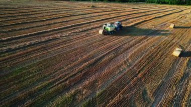 Agriculture tractor making hay bales works on the field. Aerial view of baling, baler, hay collection. High quality 4k footage
