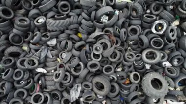Eski araba lastiklerinden oluşan bir hurdalığın havadan görünüşü. Lastik atığı üzerinde yavaş çekim. Atık lastiklerin işlenmesi için endüstriyel fabrika. Çevre kirliliği, Ekoloji, Geri Dönüşüm. Yüksek kalite 4k