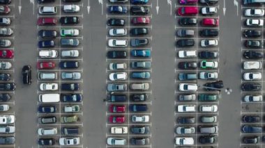 Alışveriş merkezinin yakınındaki büyük bir otoparkın hızlandırılmış hava görüntüsü. Arabalar alışveriş merkezinin yakınındaki otoparkta dolanıyor. Yüksek kalite 4k görüntü