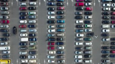 Alışveriş merkezinin yakınındaki büyük bir otoparkın hızlandırılmış hava görüntüsü. Arabalar alışveriş merkezinin yakınındaki otoparkta dolanıyor. Yüksek kalite 4k görüntü