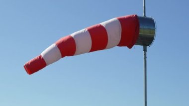 Windsock açık mavi gökyüzüne karşı rüzgarda sallanıyor. Havalimanı rüzgar göstergesinin yakın görüntüsü rüzgar yönünü ve gücünü gösteriyor. 4k görüntü