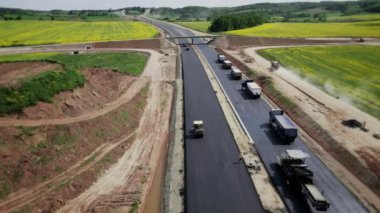 Otomobil otoyolu inşa eden inşaat ekipmanlarının havadan görüntüsü. Ağır ekipmanlar, yeni bir asfalt tabakası açıyorlar. 4k görüntü