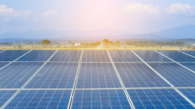 Kirli güneş panelleri ve arka planda dağ manzarası ve sabah güneşi.