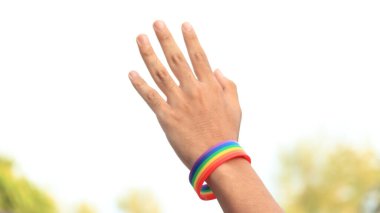 LGBT gurur konseptinde aşkı göstermek için işaret yapan ellerde gökkuşağı bileklikleri var.                                                     