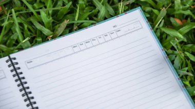 Çimlerin üzerinde kopyalama alanı olan beyaz defter kağıdı                              