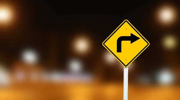 Yellow sign with right turn direction arrow on dark night blur background