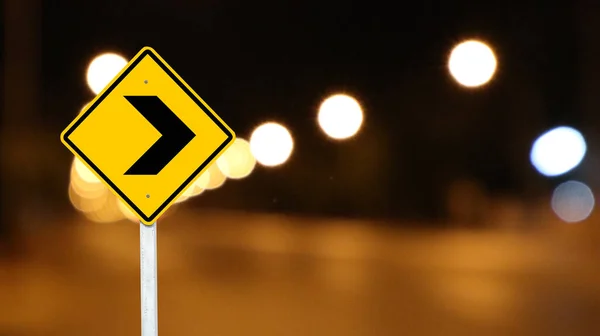 Yellow sign with right direction arrow on dark night blur background