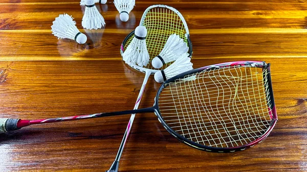 Badminton shuttle cocks and broken badminton rackets on brown wooden background
