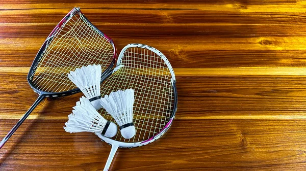 Badminton shuttle cocks and broken badminton rackets on brown wooden background