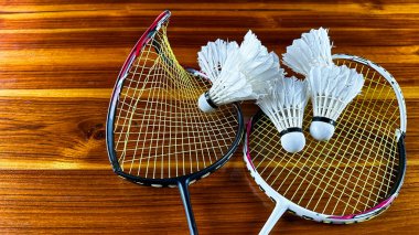 Close up of broken badminton rackets and white badminton shuttle cocks on brown wooden background