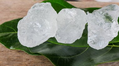 Crystal clear alum cubes or Potassium alum on green leaves chemical compound substance concept for beauty spa and underarm treatment industrial                               