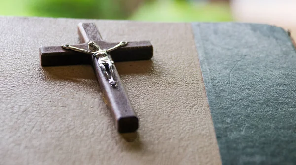 在背景模糊的旧书上画上深褐色的木制十字架 — 图库照片