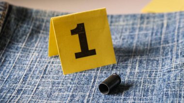 Bulanık kot pantolon üzerindeki tabanca mermileri ve arka planda bir numaralı görüntü, suç ve soruşturma konsepti. yumuşak odak