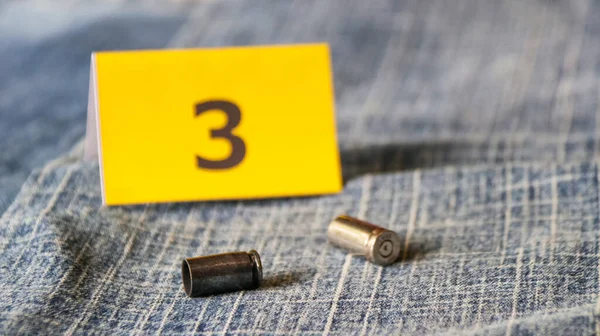 Pistol bullet shells on blur blue jeans and number three display in background, concept for criminal and investigation. soft focus