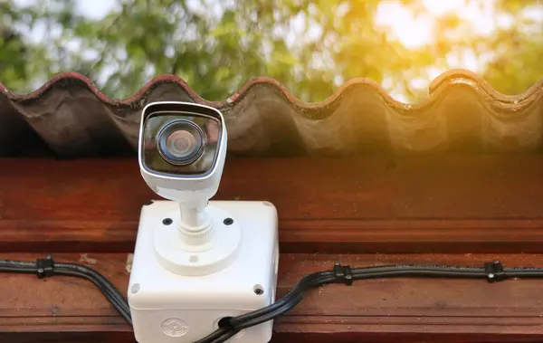 Dirty surveillance camera installed at a house to provide safety for resident with blur leaves background