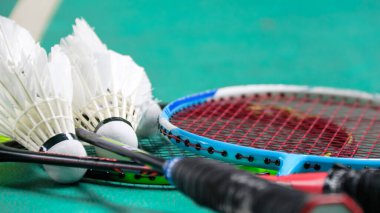 Beyaz badminton mekikleri ve yeşil zeminde badminton raketleri