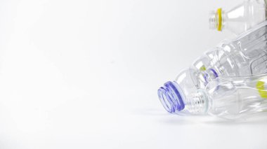 Beyaz bir yüzeyde geri dönüşümü bekleyen temiz plastik şişeler. Atıkların geri dönüşümünün, Dünya 'yı sevmenin ve doğal kaynakların korunmasının önemini vurgular.