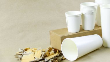 Beyaz kağıt kahve fincanı, kullanılmış kağıt ve kahverengi bir yüzey üzerinde geri dönüşümü bekleyen karton kutu. Atıkların geri dönüşümünü teşvik eder, Dünya 'yı kurtarır ve doğal kaynakları korur..