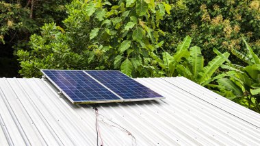Metal bir çatının üzerine kurulmuş güneş pili panelleri, sürdürülebilir enerji kullanımı ve doğal kaynakların korunması kavramını vurguluyor. Çevre dostu uygulamaları göstermek için ideal.