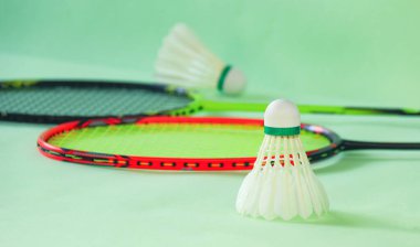 Badminton mekik horozları yeşil arka planda raketlerle spor ve küresel rekabet ruhunu, atletizmin özünü ve sporda mükemmelliği sembolize ediyor..