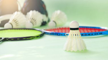 Beyaz badminton mekikleri ve yeşil arka planda badminton raketleri