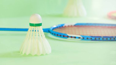 Beyaz badminton mekikleri ve yeşil arka planda badminton raketleri