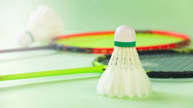 Beyaz badminton mekikleri ve yeşil arka planda badminton raketleri