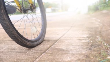 Bisikletin tekerleği, yolun kenarındaki beton kaldırımda düz bir park yeri, tamir edilmesi gerekiyor, durgunluk anı ve beklenmedik bir duraksama..