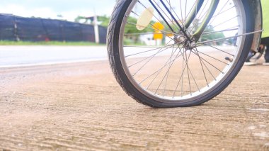 Bisikletin tekerleği, yolun kenarındaki beton kaldırımda düz bir park yeri, tamir edilmesi gerekiyor, durgunluk anı ve beklenmedik bir duraksama..