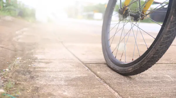 stock image Wheel of a bicycle is flat parking on concrete sidewalk beside a road, need to be repaired, the moment of stillness and an unexpected pause in a journey.