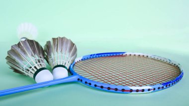 Yakın plan badminton topu ve yeşil arka planda badminton raketi. Badminton aşığını geliştirme ve egzersiz kavramı.