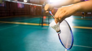 Beyaz badminton mekikleri kapalı badminton kortunda eller tarafından servis ediliyor. Badminton yarışma egzersizini ve sevgililerini geliştirme kavramı.